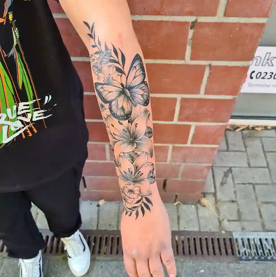 Person mit neutralem Ausdruck, Arm mit schwarzem Blumen und Schmetterling Tattoo
